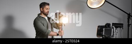 Ein Mann richtet sorgfältig Studioausrüstung ein, um atemberaubende Bilder in einer gemütlichen Umgebung aufzunehmen. Stockfoto