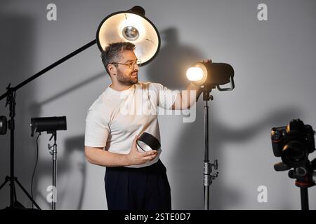 Man stellt Beleuchtungsgeräte in einem gut ausgestatteten Studio auf, um sich auf eine Fotosession vorzubereiten. Stockfoto