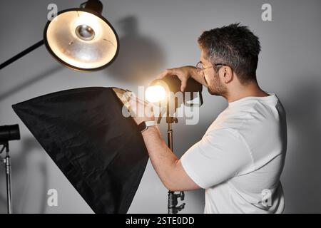 Ein Experte für Fotografie stellt eine Lichtquelle ein, um die visuelle Wirkung seiner Arbeit zu verbessern. Stockfoto