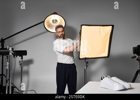 Ein Profi richtet eine Softbox-Beleuchtung ein, um Schuhe in einem Studio kreativ einzufangen. Stockfoto