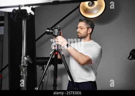 Ein erfahrener Mitarbeiter stellt eine Kamera auf einem Stativ ein und ist bereit für eine aufregende Session im Studio. Stockfoto
