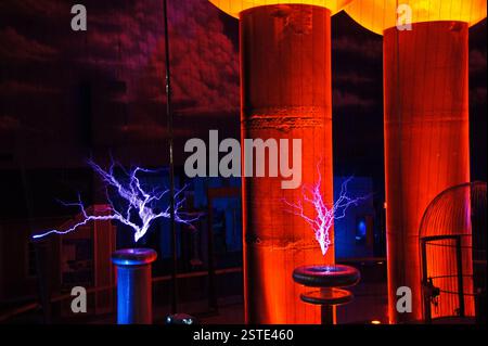 Tesla Coil funkelt in einem dunklen Raum. Rotes und blaues Licht beleuchtet die Szene. Eine kraftvolle Anzeige von Elektrizität in Boston. Die Funken ähneln Stockfoto