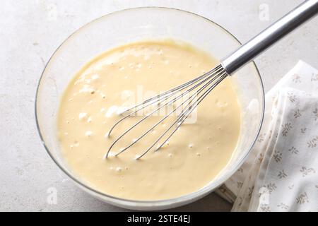 Schneebesen und eine Schüssel Teig auf grauem Tisch, über der Ansicht Stockfoto