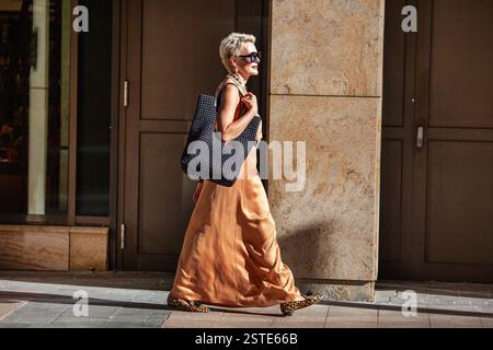 Stilvolle Reife Frau mit kurzen Friseurspaziergängen, mit Sommer Beige Maxikleid und großer schwarzer Handtasche. Mode-Modus in der Stadt. Stockfoto