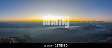 Luftaufnahme eines Bildes des süßen Himmels bei Sonnenaufgang über einem Tal aus Nebel. Hohe Gipfel wunderbarer Morgensonnenaufgang Natur Landschaft. Wunderschöner tropischer Sonnenuntergang Stockfoto