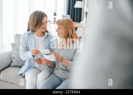 Alte Fotos ansehen. Mutter und Tochter sind zu Hause zusammen. Stockfoto