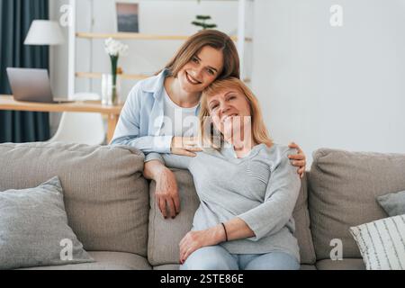 Lächelnd und in die Kamera schauend. Mutter und Tochter sind zu Hause zusammen. Stockfoto