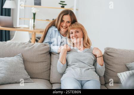 Lächelnd und in die Kamera schauend. Mutter und Tochter sind zu Hause zusammen. Stockfoto