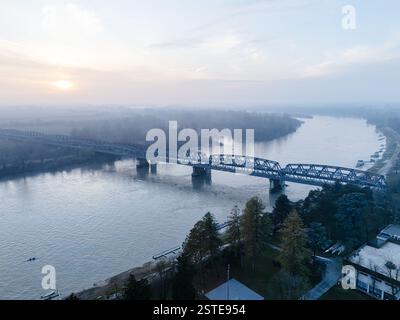 Cremona, Italien - 9. Februar 2025 aus der Vogelperspektive auf den Fluss Po in Cremona, Italien, mit einem ruhigen Wintersonnenuntergang mit einer Brücke, die die Ruhe überspannt Stockfoto