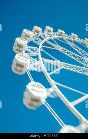 Motion Unschärfe erfasst ein dynamisches Riesenrad vor einem klaren blauen Himmel und vermittelt ein Gefühl von Unterhaltung und Spannung Stockfoto