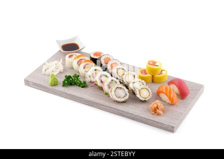 Eine vielfältige Auswahl an Sushi-Brötchen und Sashimi-Stücken, kunstvoll auf einem hölzernen Serviertablett angeordnet, kombiniert mit Sojasauce, Wasabi und eingelegtem Ingwer Stockfoto
