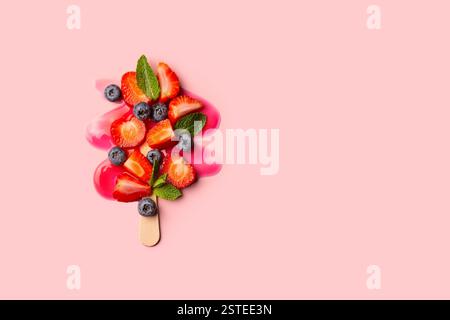 Ein Erdbeereis mit verschiedenen bunten Früchten, die eine Eiskugel nachahmen, auf rosa Hintergrund. Stockfoto