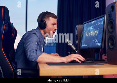 Konzentriert auf das Spielen. Man streamt FPS-Shooter-Spiel zu Hause. Stockfoto
