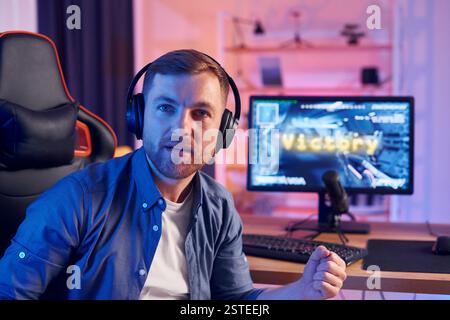 Der Mann gewinnt dieses Spiel. Online-Streamer spielt FPS-Shooter zu Hause. Stockfoto