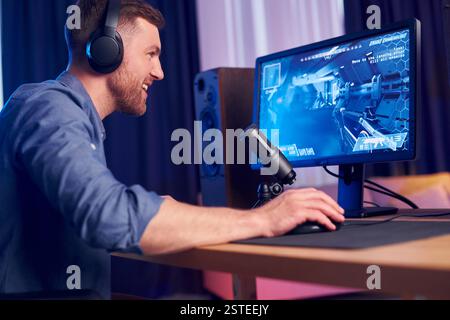 Konzentriert auf das Spielen. Man streamt FPS-Shooter-Spiel zu Hause. Stockfoto