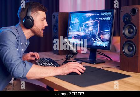 Konzentriert auf das Spielen. Man streamt FPS-Shooter-Spiel zu Hause. Stockfoto