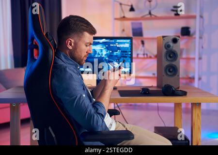 Auf dem Stuhl sitzen. Online-Streamer, der FPS-Shooter zu Hause spielt. Stockfoto