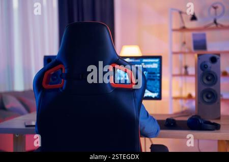 Auf dem Stuhl sitzen. Online-Streamer, der FPS-Shooter zu Hause spielt. Stockfoto