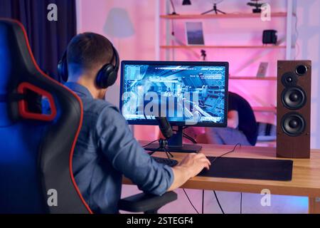 Auf dem Stuhl sitzen. Online-Streamer, der FPS-Shooter zu Hause spielt. Stockfoto