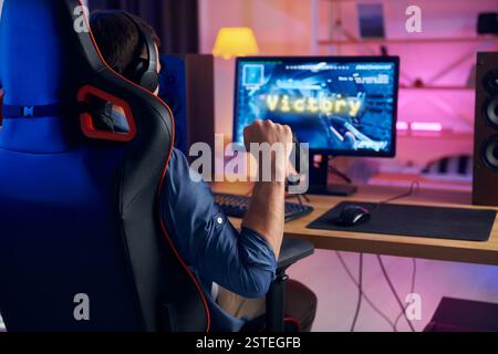 Auf dem Stuhl sitzen. Online-Streamer, der FPS-Shooter zu Hause spielt. Stockfoto