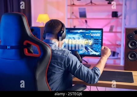 Blick von hinten. Online-Streamer, der FPS-Shooter zu Hause spielt. Stockfoto