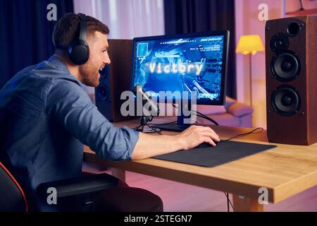 Der Mann gewinnt dieses Spiel. Online-Streamer spielt FPS-Shooter zu Hause. Stockfoto