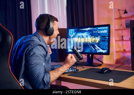 Der Mann gewinnt dieses Spiel. Online-Streamer spielt FPS-Shooter zu Hause. Stockfoto