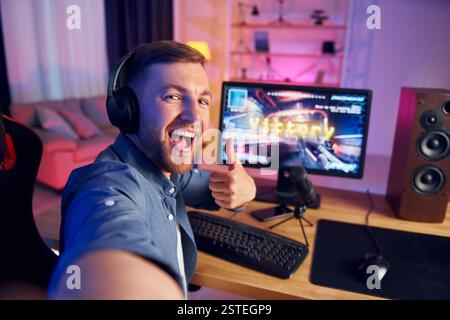 Selfie machen. Schreiend und feiert den Sieg. Online-Streamer, der FPS-Shooter zu Hause spielt. Stockfoto
