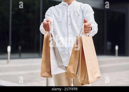 Einkaufstag. Ein stilvoller junger Mann ist draußen mit Taschen. Stockfoto