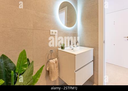 Ein Bild von einem Waschbecken mit beleuchtetem Spiegel und Steinfliesen in einem mediterranen Ferienhaus Stockfoto