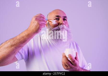Älterer alter Mann mit grauem Bart-Schönheitsprofil im Studio - stilvoller älterer männlicher Erwachsener, der Hautpflegebehandlungen macht, Konzepte über ältere Menschen und Lebensstil Stockfoto