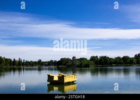 Eine schwimmende gelbe Skulptur, die auf einem Teich im Denver Botanic Gardens mit dramatischem Kontrastlicht schwingt Stockfoto