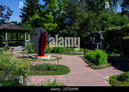 Eine auffällige rote Calder-Kopf- und Gesichtsskulptur steht im Kontrast zum umliegenden Grün des botanischen Gartens in Denver, Colorado. Stockfoto