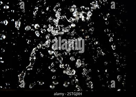 Wassertropfen fliegen in der Luft mit defokussierten Lichter auf Hintergrund Stockfoto