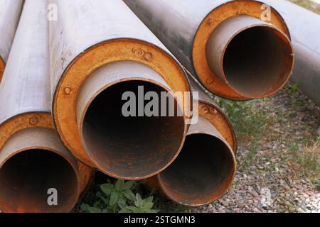 Wasserrohre aus Stahl mit PVC-Isoliermantel im Stapel auf dem Boden auf der Baustelle Stockfoto