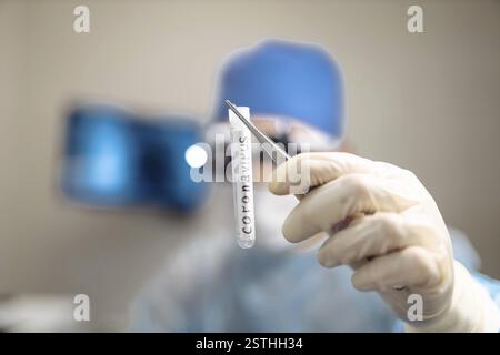 Laborwissenschaftler, der ein mit Coronavirus gekennzeichnetes Teströhrchen in Handschuhen hält Stockfoto