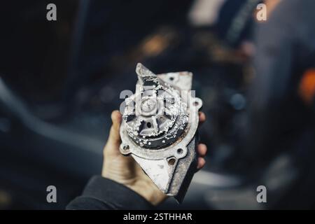 Person, die ein Autoteil aus Metall hält, konzentriert sich auf die Reparatur im Fahrzeug Stockfoto