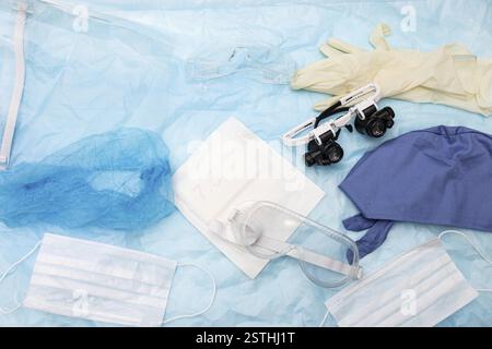 Mischung aus medizinischer Schutzausrüstung wie Masken, Kappen und Schutzbrillen auf blauer Oberfläche Stockfoto
