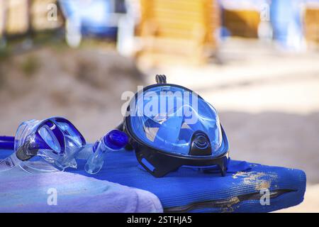 Eine blaue Tauchermaske auf einem Handtuch am Strand mit Sand im Hintergrund Stockfoto