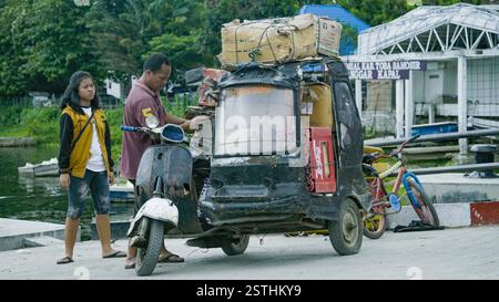 26. Mai 2017. North Sumatra IDN – Ein dreirädriger Roller-Fahrer, der verschiedene Kisten in der Nähe eines Ufers entlädt und eine geschäftige Logistikszene in einem urb zeigt Stockfoto