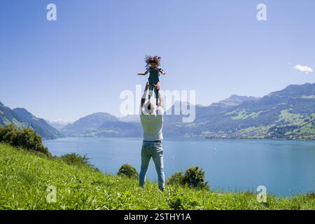 Glücklicher Vater, der mit Kind auf der Natur spielt. Vater hebt sich, wirft ein Kind in die Luft. Vater hält Kind mit Liebe in den Armen. Kind lacht und genießt Stockfoto