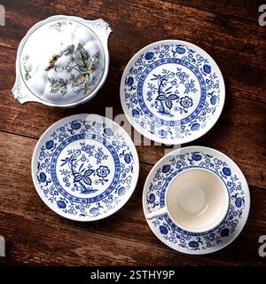 Ein Set blau-weißer Teller und eine weiße Tasse stehen auf einem Holztisch Stockfoto