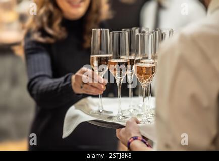 Junger Kellner mit einem Tablett mit Champagner oder Prosecco bei einer Hochzeit oder Gala und einem Begrüßungsgetränk Stockfoto