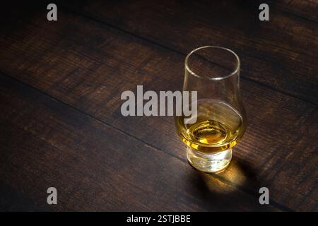 Nahaufnahme von Single Malt Whiskey oder Scotch Whisky Verkostungsglas auf dunklem Holztisch Stockfoto