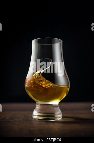 Nahaufnahme von Single Malt Whiskey oder Scotch Whisky Verkostungsglas auf dunklem Holztisch Stockfoto