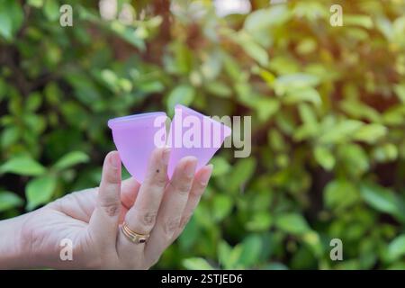 Nahaufnahme einer Frauenhand mit Menstruationstassen in einer Hand Gynäkologiekonzept, in einem verschwommenen Hintergrund. Stockfoto