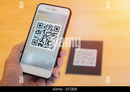 Männliche Hand, die ein Mobiltelefon mit qr-Code auf dem Bildschirm hält. Scannen des qr-Codes. Selektiver Fokus auf Telefon. Stockfoto