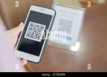 Frau bezahlt mit qr-Code. Nahaufnahme der Hand des Kunden, die Zahlung per Smartphone tätigt und Code scannt. Stockfoto