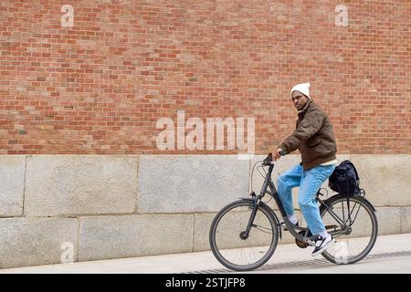 Junger, stilvoller Mann, der Fahrrad fährt in urbaner Umgebung, nachhaltiger Transport und aktives Lifestyle-Konzept Stockfoto