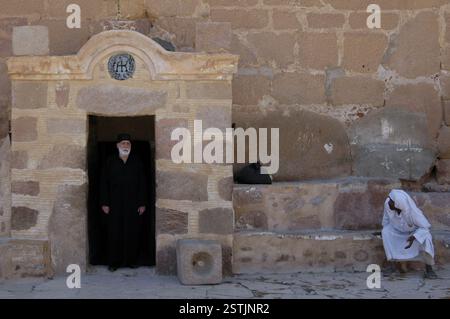 Ein griechisch-orthodoxer Priester tritt vor den hinteren Eingang zum Katharinenkloster aus dem 5.. Jahrhundert am Fuße des Berges Sinai in Ägypten Stockfoto